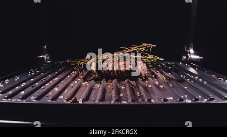 Délicieux bifteck de viande juteuse sur le gril. Faire cuire au bœuf à la sauce au roaster électrique, au romarin, au poivre noir et au sel. Ralenti. Banque D'Images