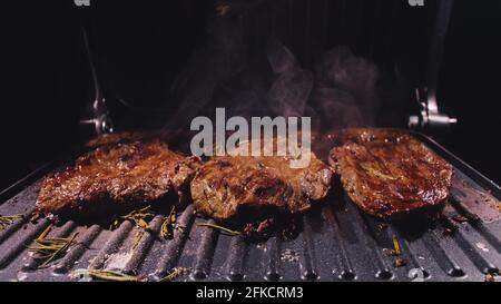 Délicieux bifteck de viande juteuse sur le gril. Faire cuire au bœuf à la sauce au roaster électrique, au romarin, au poivre noir et au sel. Ralenti. Banque D'Images