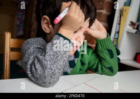 Royaume-Uni, un garçon frustré qui fait ses devoirs Banque D'Images