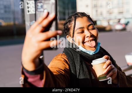 Une femme qui colle la langue prend le selfie à l'extérieur Banque D'Images