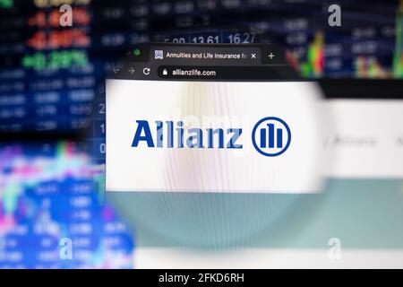 Le logo de la société Allianz sur un site Web présentant des développements flous sur le marché boursier en arrière-plan, vu sur un écran d'ordinateur à travers une loupe Banque D'Images