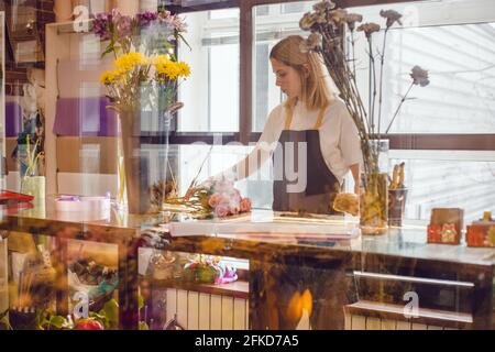 Fleuriste de fille recueille une composition de fleurs dans un magasin de fleurs. Banque D'Images