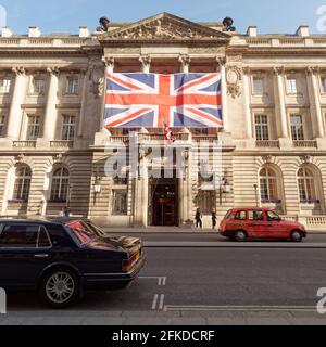 Londres, Grand Londres, Angleterre - 24 2021 avril : Union Jack exposé dans Pall Mall, qui se reflète dans la fenêtre arrière d'une voiture lorsqu'un taxi rouge passe. Banque D'Images