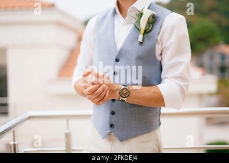 Le marié dans une chemise et la veste avec une boutonnière se tient sur le balcon le matin avant le mariage cérémonie Banque D'Images