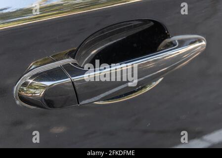 Poignée de porte brillante et profilée sur l'extérieur d'une voiture de luxe noire aux lignes épurées. Banque D'Images
