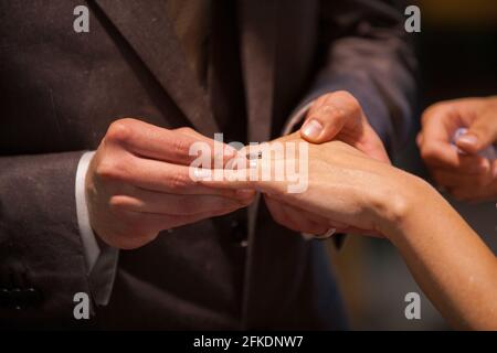 Gros plan de la mariée mettant un anneau de mariage sur le doigt du marié. Couple échanger des anneaux de mariage. Photo de haute qualité Banque D'Images