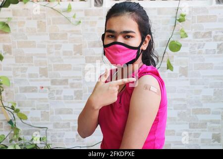 Une jeune fille indienne montre un bandage appliqué après avoir reçu la vaccination pendant une nouvelle souche de covid-19, un jeune adolescent portant un masque a reçu un vaccin coronavirus vaccin Banque D'Images