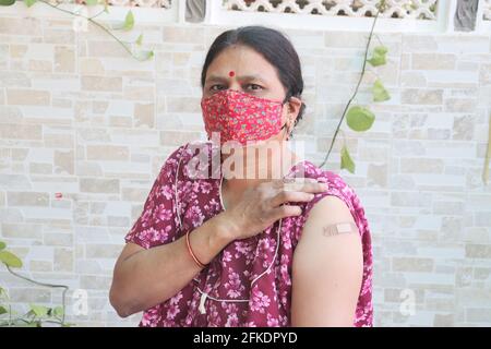 Une femme indienne montre un bandage appliqué après avoir reçu la vaccination pendant une nouvelle souche de covid-19, une femme mature portant un masque a reçu un vaccin contre le coronavirus Banque D'Images