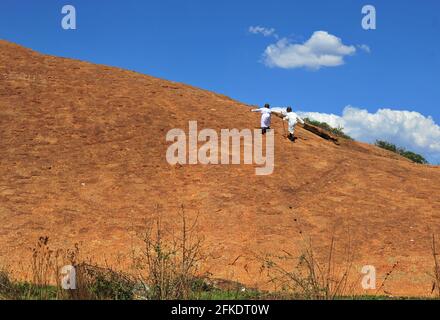 Les adorateurs africains qui mondent une colline rocheuse prient par temps clair avec le ciel bleu à Limpopo, en Afrique du Sud Banque D'Images