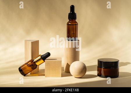 Huile essentielle naturelle ou sérum en flacons de verre brun sur podiums en bois. Médecine alternative, produit de soins de beauté pour la peau. Arrière-plan neutre. Banque D'Images