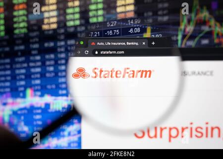 Logo de la société State Farm sur un site Web avec des développements flous du marché boursier en arrière-plan, vu sur un écran d'ordinateur à travers une loupe Banque D'Images