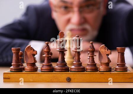 Un vieux employé d'homme d'affaires jouant aux échecs sur le lieu de travail Banque D'Images