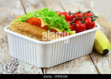 Boîte à lunch saine contenant un sandwich au fromage à grains entiers, des tomates cerises et de la banane Banque D'Images