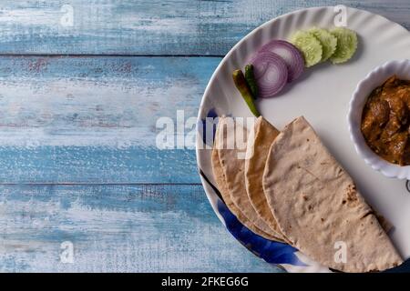 Vue de dessus du rôti et du curry avec salade servi dans une assiette sur table en bois bleu Banque D'Images