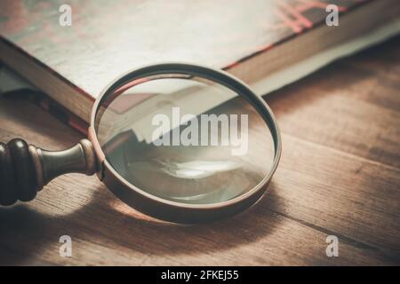 Verre grossissant vintage penchée au coin d'un vieux Livre Banque D'Images