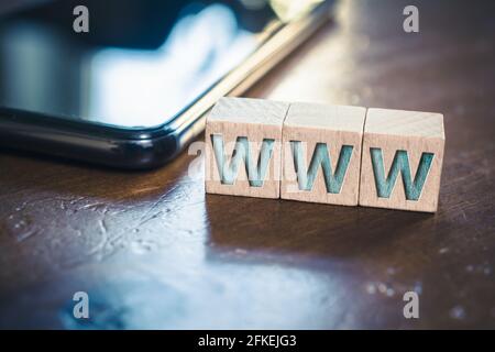 WWW écrit sur des blocs de bois à côté D'UN smartphone sur Une table Banque D'Images