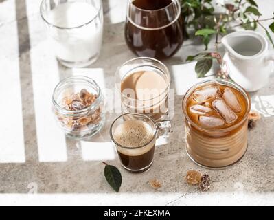 Délicieux café glacé au lait, à la crème et avec différents types de café, fond gris avec espace de copie. Café glacé avec lait, espresso, bouchon Banque D'Images