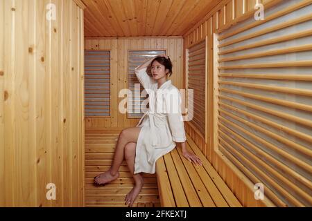 Jolie jeune femme en peignoir de détente dans le sauna chaud de hôtel spa Banque D'Images