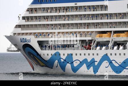 01 mai 2021, Mecklembourg-Poméranie occidentale, Warnemünde : l'équipage se tient à bord et se déchaîne alors que l'« AIDAsol » quitte la station balnéaire de la mer Baltique après un séjour d'une semaine au terminal de croisière. Le navire a visité Warnemünde sans passagers pour des raisons de corona et a testé le nouveau système d'alimentation terrestre, qui sera en mesure de fournir de l'électricité aux navires de croisière à l'avenir. Photo: Bernd Wüstneck/dpa-Zentralbild/dpa Banque D'Images