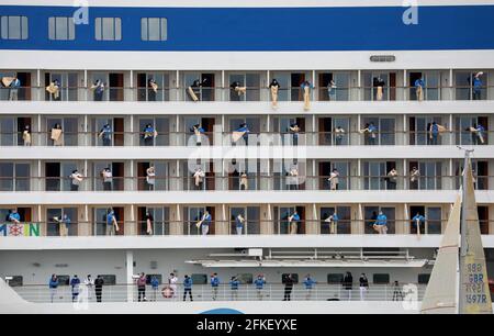 01 mai 2021, Mecklembourg-Poméranie occidentale, Warnemünde : l'équipage se tient à bord et se déchaîne alors que l'« AIDAsol » quitte la station balnéaire de la mer Baltique après un séjour d'une semaine au terminal de croisière. Le navire a visité Warnemünde sans passagers pour des raisons de corona et a testé le nouveau système d'alimentation terrestre, qui sera en mesure de fournir de l'électricité aux navires de croisière à l'avenir. Photo: Bernd Wüstneck/dpa-Zentralbild/dpa Banque D'Images