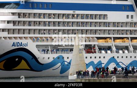 01 mai 2021, Mecklembourg-Poméranie occidentale, Warnemünde : l'équipage se tient à bord et se déchaîne alors que l'« AIDAsol » quitte la station balnéaire de la mer Baltique après un séjour d'une semaine au terminal de croisière. Le navire a visité Warnemünde sans passagers pour des raisons de corona et a testé le nouveau système d'alimentation terrestre, qui sera en mesure de fournir de l'électricité aux navires de croisière à l'avenir. Photo: Bernd Wüstneck/dpa-Zentralbild/dpa Banque D'Images