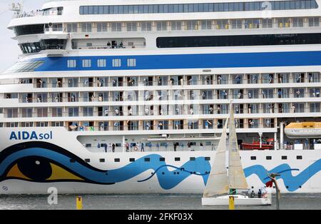 01 mai 2021, Mecklembourg-Poméranie occidentale, Warnemünde : l'équipage se tient à bord et se déchaîne alors que l'« AIDAsol » quitte la station balnéaire de la mer Baltique après un séjour d'une semaine au terminal de croisière. Le navire a visité Warnemünde sans passagers pour des raisons de corona et a testé le nouveau système d'alimentation terrestre, qui sera en mesure de fournir de l'électricité aux navires de croisière à l'avenir. Photo: Bernd Wüstneck/dpa-Zentralbild/dpa Banque D'Images