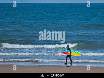 Pease Bay, frontières écossaises, Écosse, météo britannique. 1er mai 2021. Soleil sur la côte pour ce sufer mâle marchant sur la plage avec un surf coloré, matin ensoleillé, température 9 degrés centigrade Banque D'Images