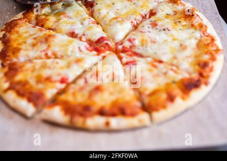 Gros plan et mise au point sélective d'un plat cuit à la maison croquer quatre pizzas de fromage coupées en tranches sur un planche à découper en bois Banque D'Images