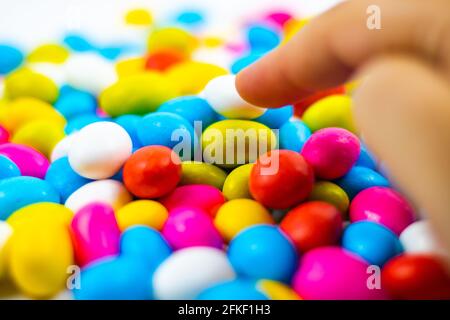 Une femme piquant un bonbon dans un bol de bonbons en particulier arrière-plan blanc Banque D'Images