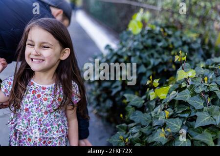 Une petite fille heureuse et mignonne en robe fleurie debout à côté à une douille Banque D'Images