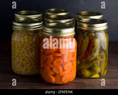 Divers types de légumes en conserve sur une table en bois dans Un environnement sombre Banque D'Images