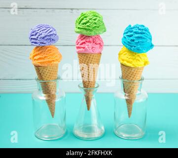 Crème glacée Rainbow Scoops dans des Cones de gaufre sur un sarcelle Tableau Banque D'Images