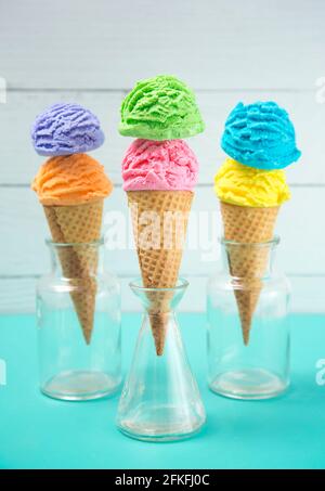 Crème glacée Rainbow Scoops dans des Cones de gaufre sur un sarcelle Tableau Banque D'Images