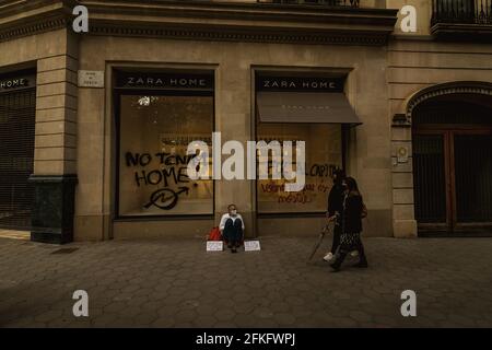 Barcelone, Espagne. 1er mai 2021. Un homme sans domicile se trouve devant un magasin ZARA, après que des militants aient peint « nous n'avons pas de maison » sur la fenêtre lors d'une manifestation contre une grande variété de groupes de gauche marquant le 1er mai à Barcelone Credit: Matthias Oesterle/Alay Live News Banque D'Images