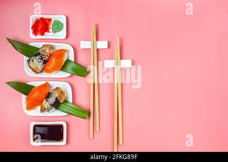 Sushi avec baguettes et sauce soja sur fond rose minimaliste. Banque D'Images