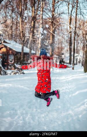 Bonne jeune femme sautant dans la neige Banque D'Images