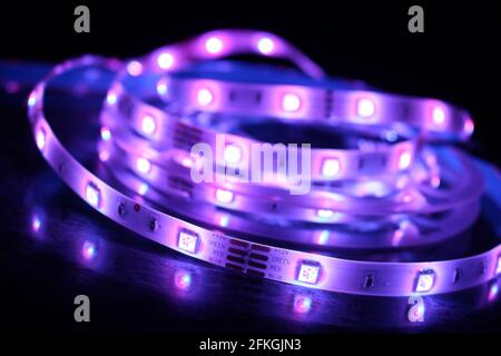 Gros plan d'une bande de silicone à LED avec lumières violettes sur fond noir Banque D'Images
