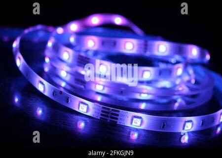 Gros plan d'une bande de silicone à LED avec lumières violettes sur fond noir Banque D'Images