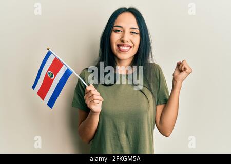 Une jeune fille hispanique portant le drapeau du costa rica criant fière, célébrant la victoire et le succès très excitée avec le bras relevé Banque D'Images