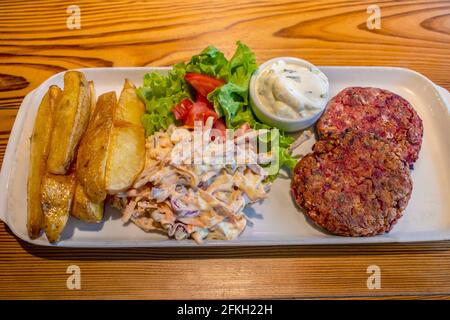 Hamburgers au quinoa et aux graines, avec pommes de terre rôties, salade fraîche et vinaigrette au fromage concombre et à la menthe (plats végétariens). Banque D'Images