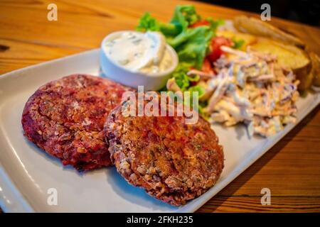 Hamburgers au quinoa et aux graines, avec pommes de terre rôties, salade fraîche et vinaigrette au fromage concombre et à la menthe (plats végétariens). Banque D'Images