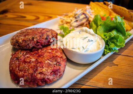 Hamburgers au quinoa et aux graines, avec pommes de terre rôties, salade fraîche et vinaigrette au fromage concombre et à la menthe (plats végétariens). Banque D'Images