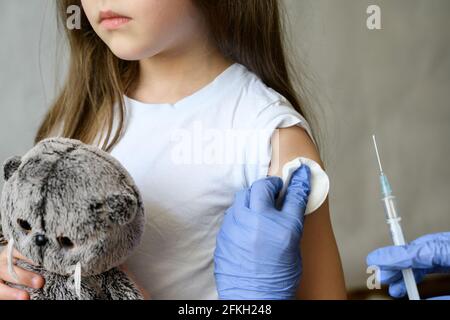 Vaccination Kid et COVID-19, petite fille mignonne pendant l'injection du vaccin coronavirus. Le médecin tient la seringue pour faire jab à l'enfant adorable. Concept de im Banque D'Images