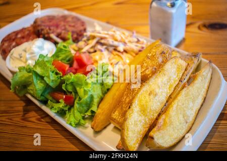 Hamburgers au quinoa et aux graines, avec pommes de terre rôties, salade fraîche et vinaigrette au fromage concombre et à la menthe (plats végétariens). Banque D'Images