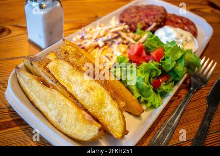 Hamburgers au quinoa et aux graines, avec pommes de terre rôties, salade fraîche et vinaigrette au fromage concombre et à la menthe (plats végétariens). Banque D'Images
