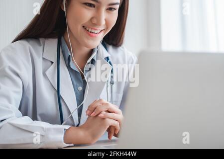 Femme thérapeute asiatique médecin est en ligne de visite avec un patient sur l'application Internet. Elle écoute et donne des conseils et explique comment traiter le Banque D'Images