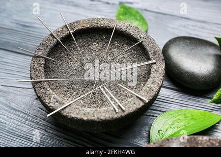 Tenez-vous debout avec les aiguilles d'acupuncture sur fond en bois Banque D'Images