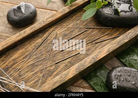 Support avec aiguilles d'acupuncture et pierres spa sur fond de bois Banque D'Images