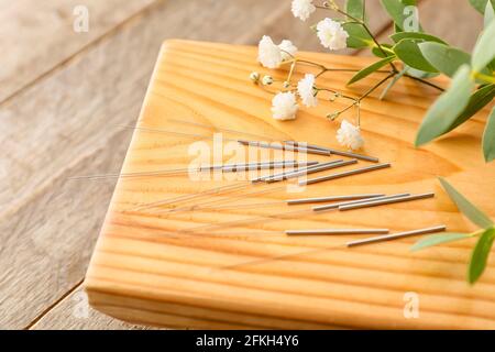 Support avec aiguilles d'acupuncture et fleurs sur fond de bois Banque D'Images