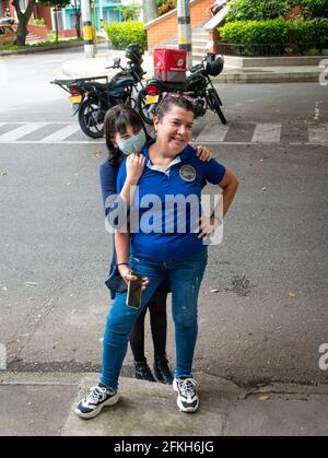 Medellin, Colombie - Mars 28 2021: Une adolescente latine portant un masque facial embrasse sa grand-mère dans la rue Banque D'Images